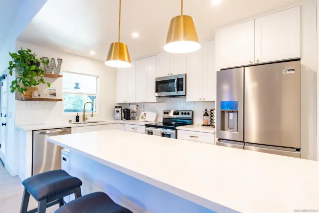a kitchen with stainless steel appliances a dining table chairs and view living room