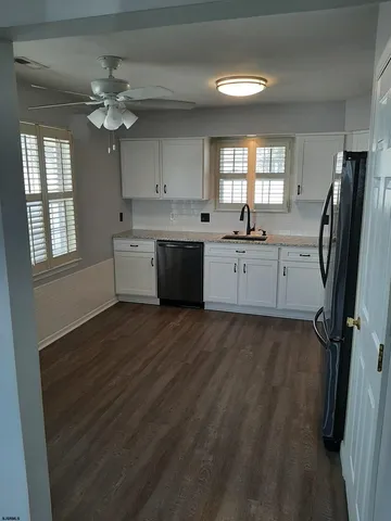 a large kitchen with a refrigerator a sink dishwasher a dining table and chairs with wooden floor