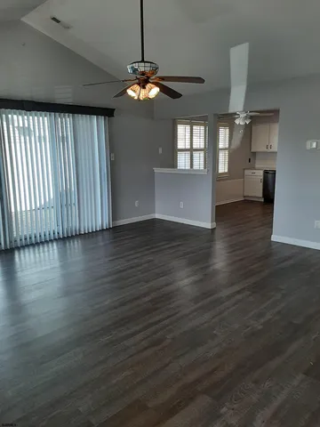 an empty room with wooden floor chandelier and windows