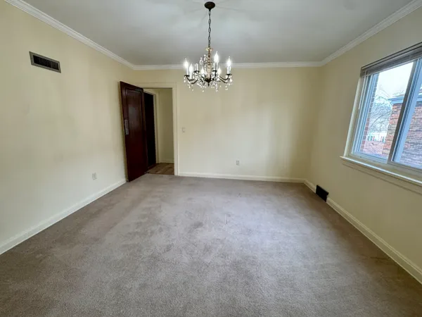 an empty room with chandelier and windows