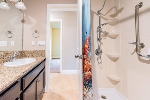 a bathroom with a granite countertop shower a sink and vanity