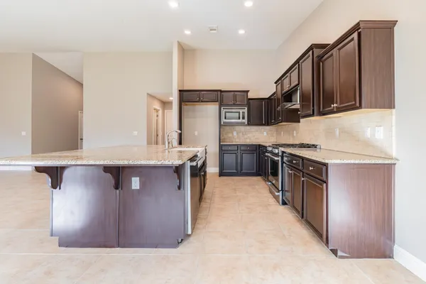 a kitchen with stainless steel appliances granite countertop a stove a sink and a refrigerator