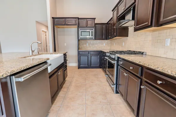 a kitchen with stainless steel appliances granite countertop a sink stove and refrigerator