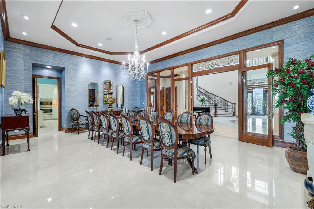 7159 Manasota Key Road Englewood, FL 34223 - Photo 14 of 50 Dining area with wallpapered walls, a raised ceiling, stairway, ornamental molding, and a chandelier