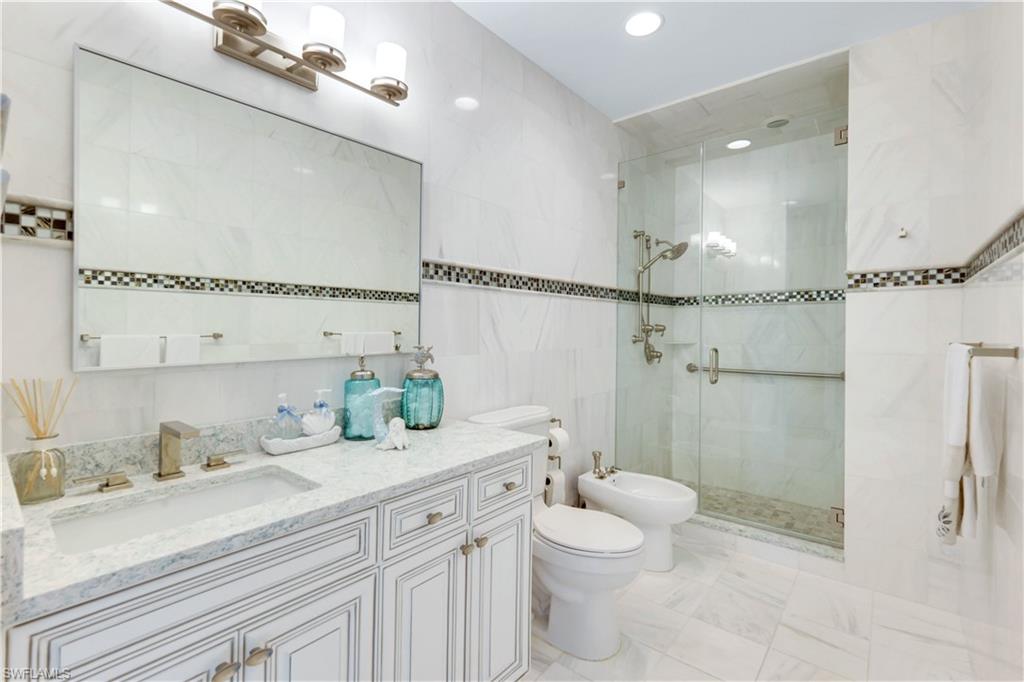 7159 Manasota Key Road Englewood, FL 34223 - Photo 32 of 50 Full bath with tile walls, a bidet, vanity, a stall shower, and recessed lighting