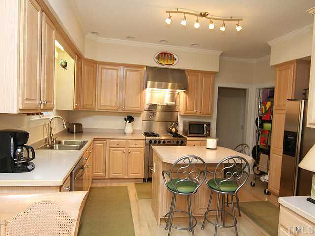The kitchen features an abundance of cabinets and an island with storage. The gas range is commercial type with a hood. Kitchen