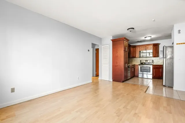 a view of kitchen with stainless steel appliances wooden floor and chair