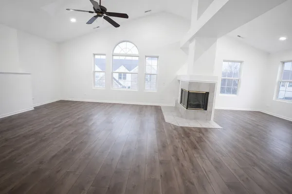 an empty room with wooden floor fireplace and windows
