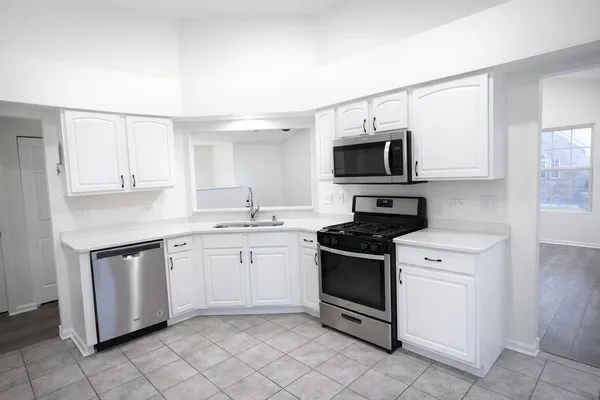 a kitchen with white cabinets and appliances