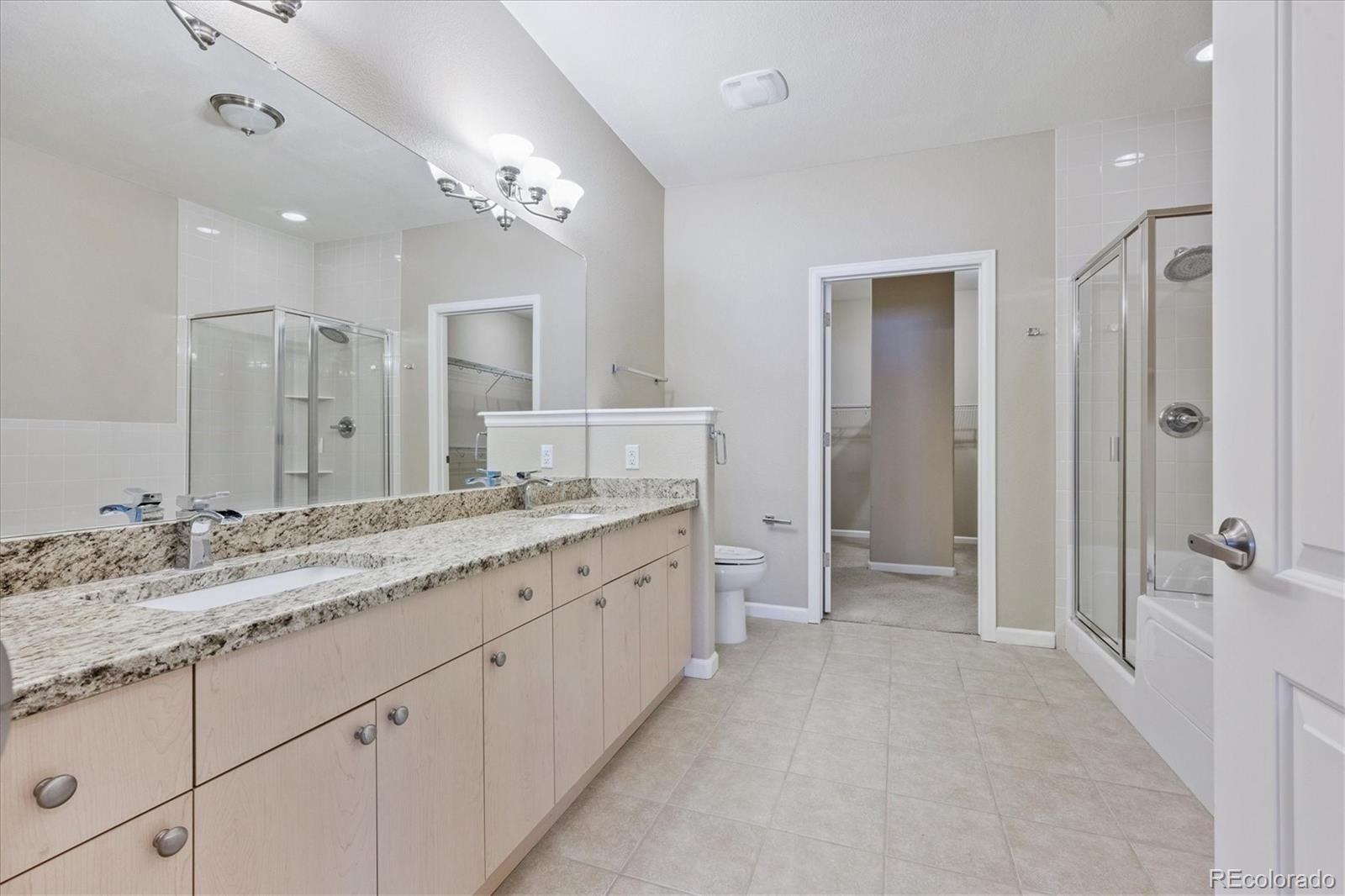 8650 Gold Peak Drive, Unit A Highlands Ranch, CO 80130 - Photo 30 of 47 a spacious bathroom with a granite countertop sink a mirror and a shower