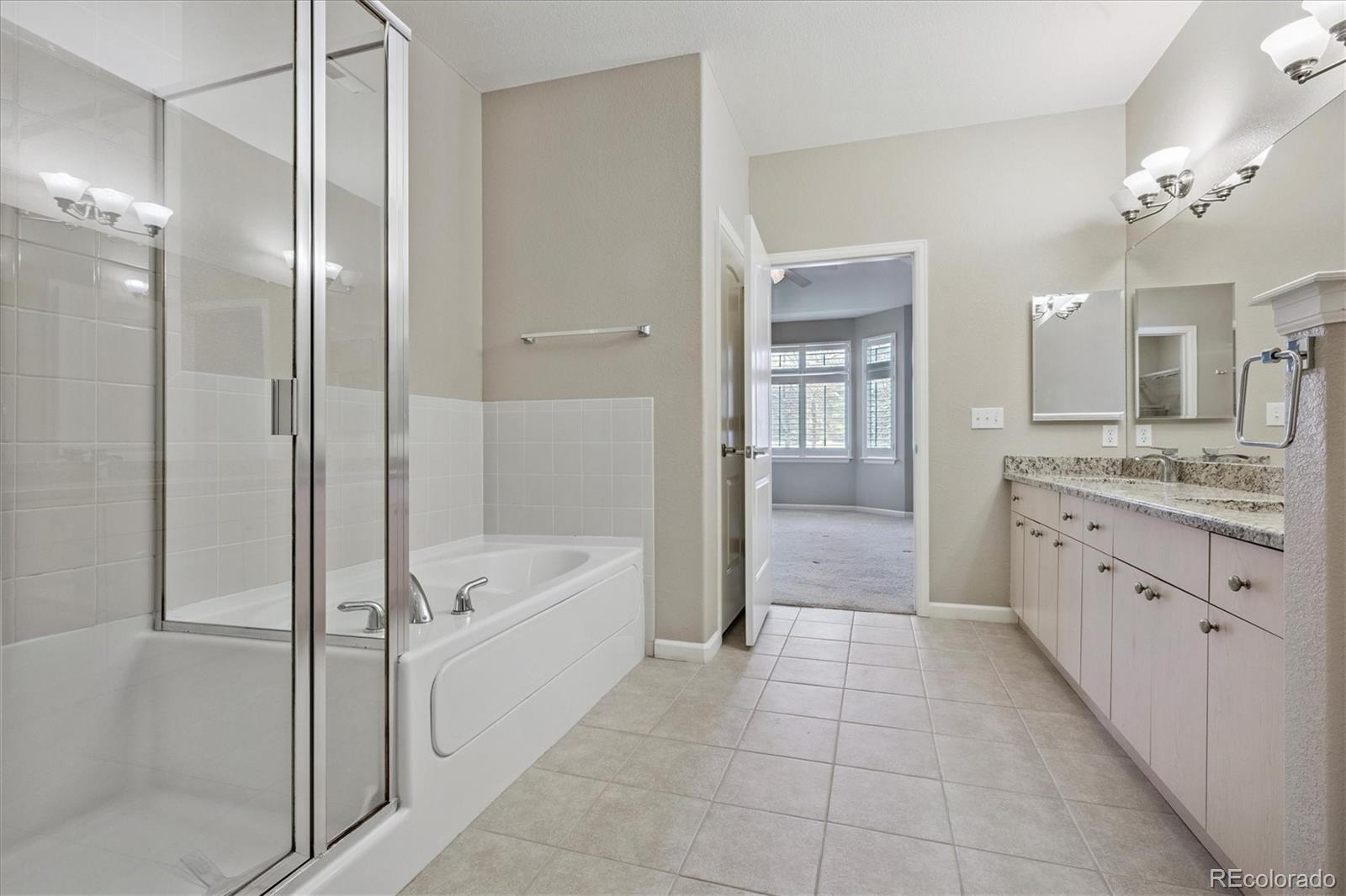8650 Gold Peak Drive, Unit A Highlands Ranch, CO 80130 - Photo 32 of 47 a bathroom with a granite countertop sink a mirror and a bathtub