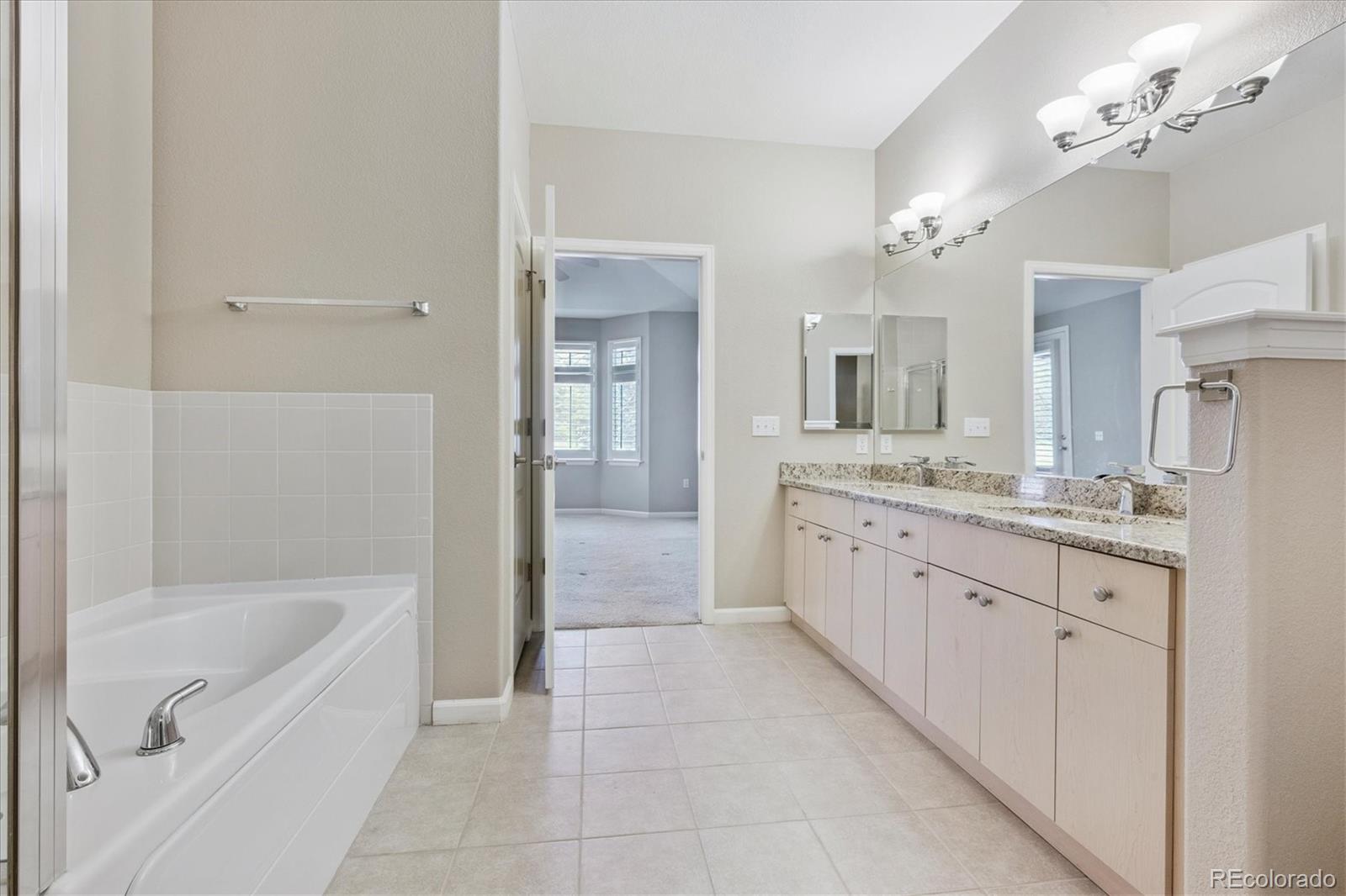 8650 Gold Peak Drive, Unit A Highlands Ranch, CO 80130 - Photo 33 of 47 a large en suite bathroom with a granite countertop double vanity sink a bathtub and shower