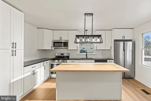a kitchen with stainless steel appliances a sink a stove a microwave a center island and cabinets