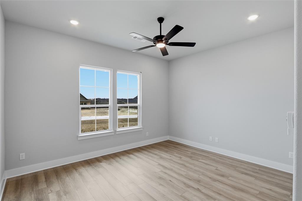812 Vly Rdg Road Van Alstyne, TX 75495 - Photo 21 of 33 an empty room with wooden floor a ceiling fan and windows