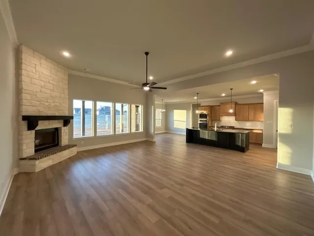 an empty room with wooden floor fireplace and windows