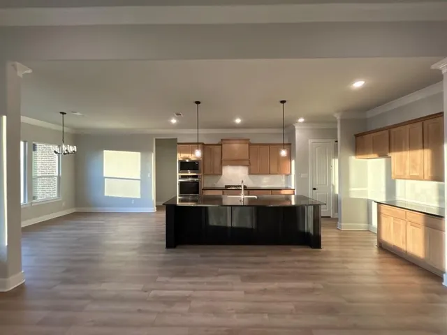 a large white kitchen with kitchen island a sink wooden floor and a large window