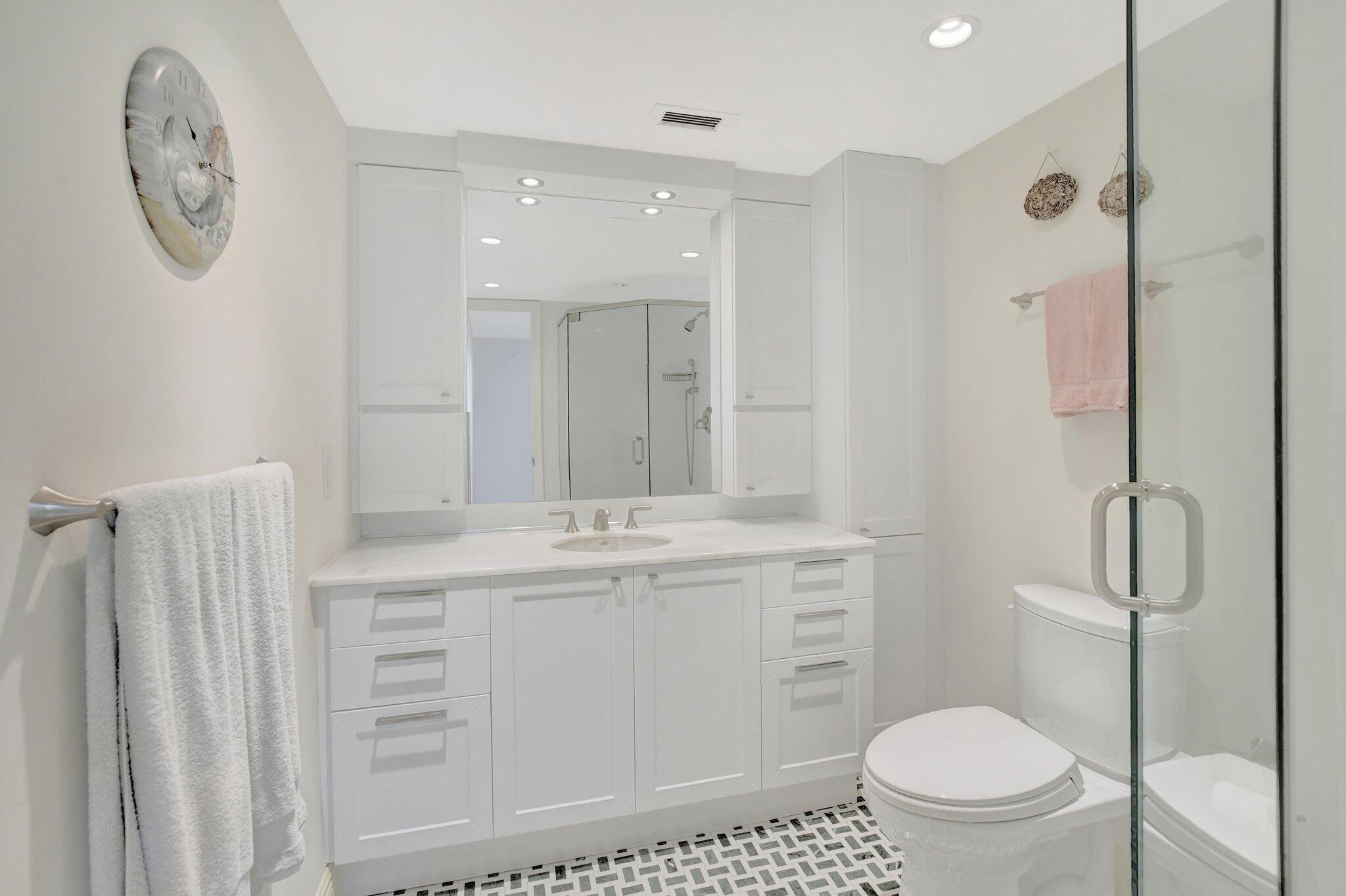 1099 South Ocean Boulevard, Unit 105 Boca Raton, FL 33432 - Photo 13 of 30 a bathroom with a toilet a sink a mirror a vanity and a shower