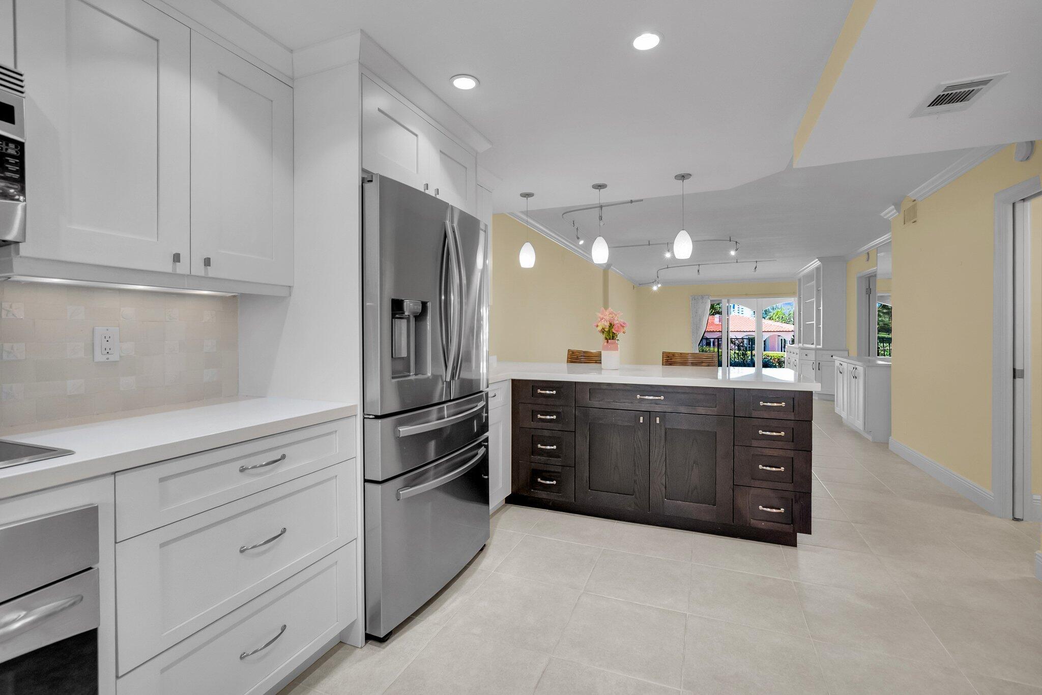 1099 South Ocean Boulevard, Unit 105 Boca Raton, FL 33432 - Photo 4 of 30 a kitchen with stainless steel appliances kitchen island granite countertop a refrigerator and cabinets