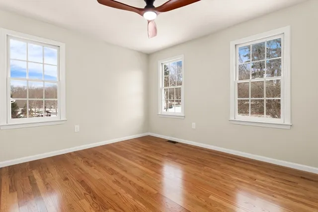 an empty room with wooden floor cabinet and windows