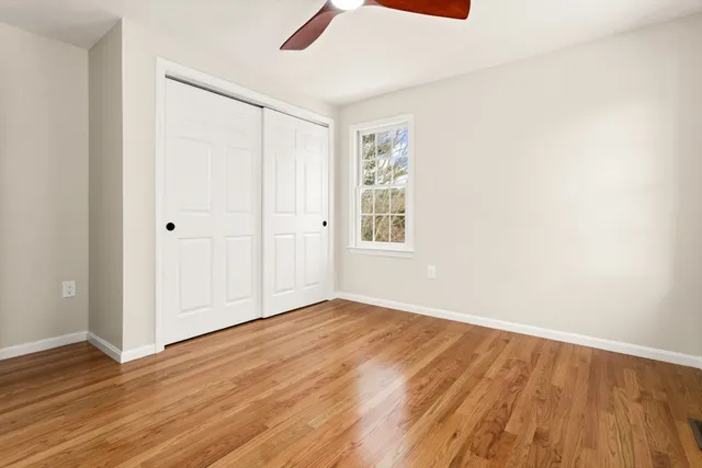 an empty room with wooden floor cabinet and windows