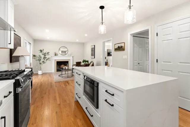 a large white kitchen with a stove a sink a refrigerator and a fireplace
