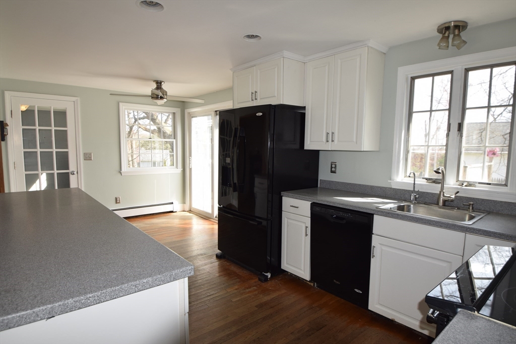 71 Rockefeller Street Randolph, MA 02368 - Photo 5 of 23 a kitchen with granite countertop a refrigerator a sink dishwasher a stove and white countertops with wooden floor