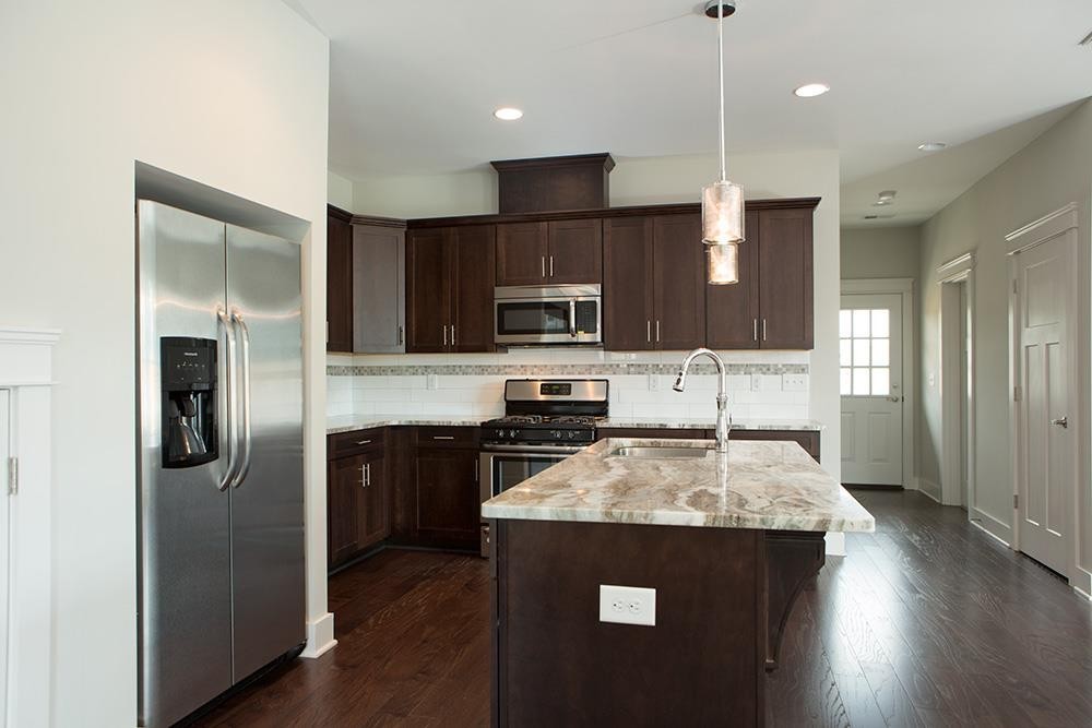 a kitchen with kitchen island granite countertop stainless steel appliances and wooden cabinets