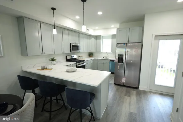 a kitchen with stainless steel appliances a refrigerator a sink a stove a dining table and chairs