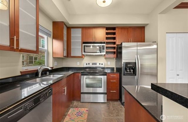 a kitchen with stainless steel appliances granite countertop a sink stove and refrigerator