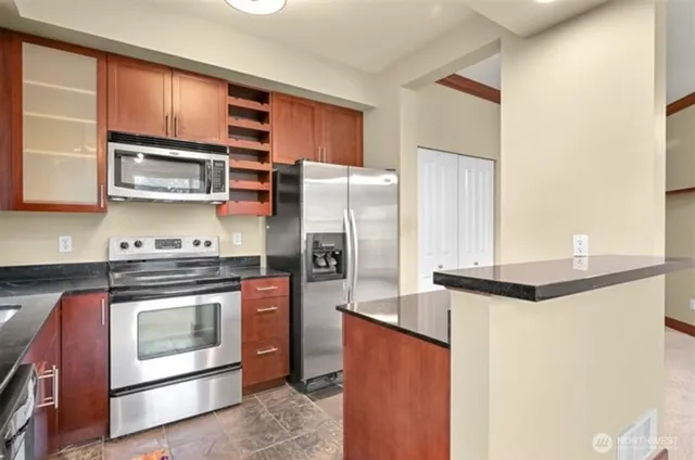 a kitchen with stainless steel appliances granite countertop a stove a refrigerator and a microwave