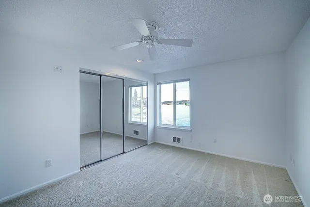 an empty room with chandelier fan and windows
