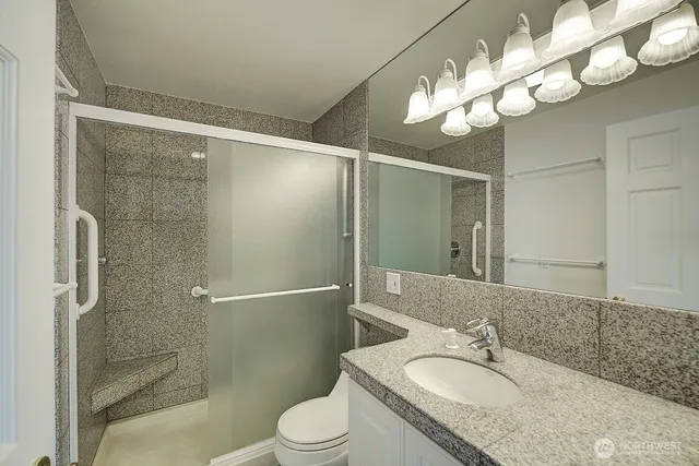 a bathroom with a granite countertop shower a sink and toilet