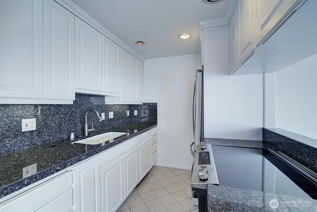 a kitchen with granite countertop a sink and a stove top oven