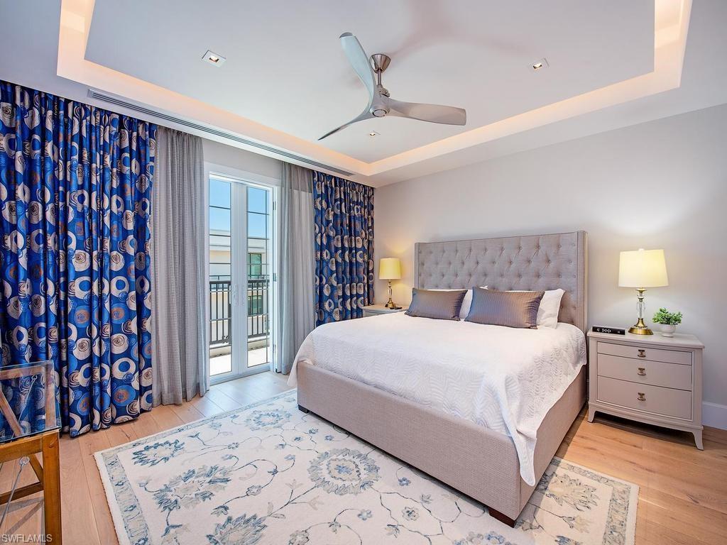490 5th Street South, Unit 101 Naples, FL 34102 - Photo 15 of 34 a bedroom with a large bed and a chandelier