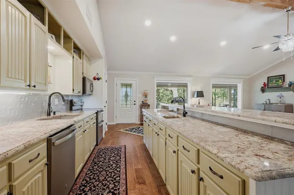 a large kitchen with granite countertop a sink stove and cabinets