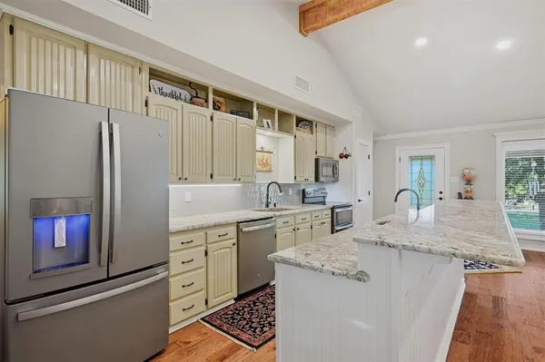 a kitchen with stainless steel appliances granite countertop a refrigerator a sink and white cabinets
