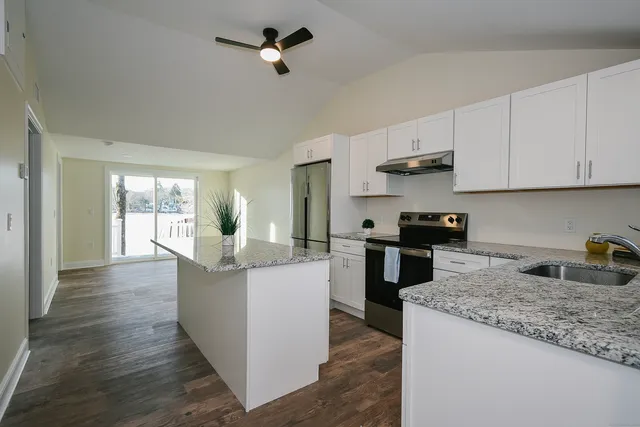 a kitchen with kitchen island granite countertop a sink cabinets and stainless steel appliances