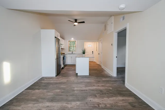 a view of a kitchen with refrigerator and wooden floor