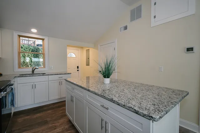 a kitchen with granite countertop a sink and white cabinets