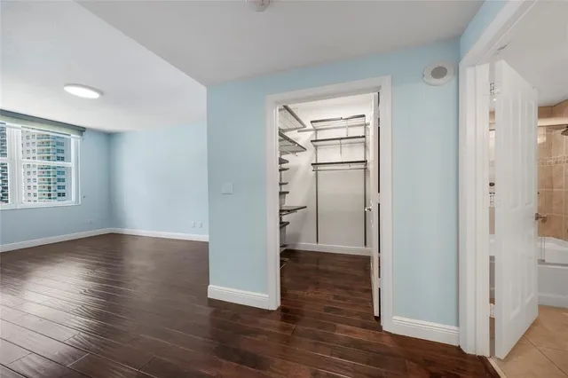 an empty room with wooden floor closet and windows