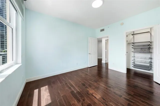 a view of an empty room with a window and wooden floor