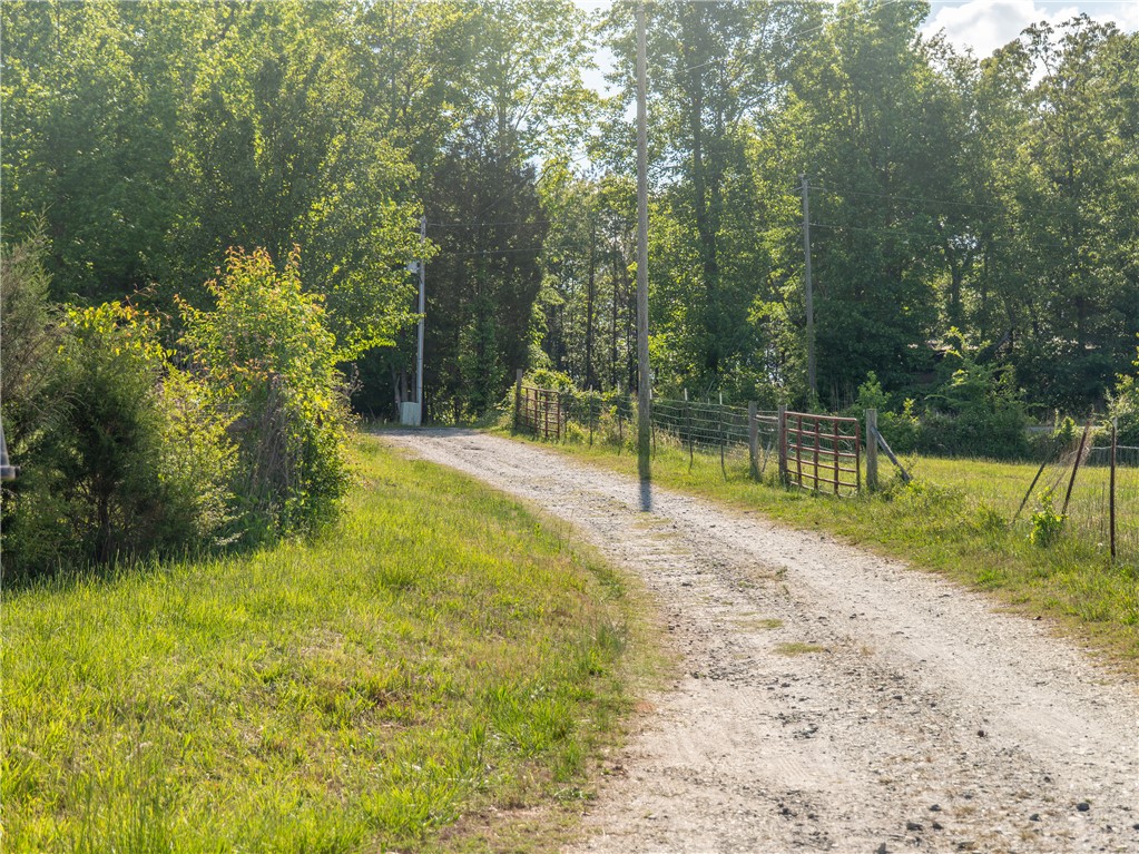 A winding gravel path leads through lush greenery and trees, creating a serene natural setting.
