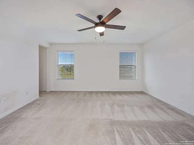 an empty room with ceiling fan and windows