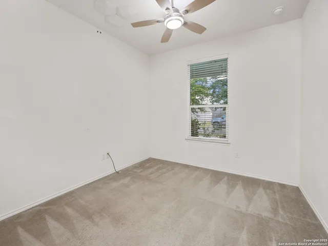 an empty room with a window and a fan