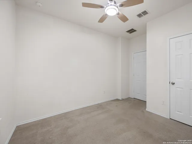 an empty room with a chandelier fan and a large window