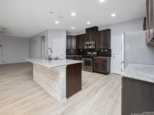 a large kitchen with stainless steel appliances kitchen island granite countertop a large counter top and wooden floors
