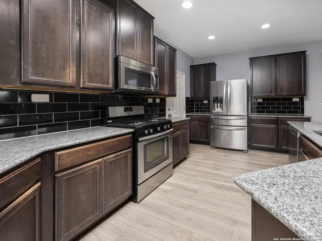 a kitchen with granite countertop wooden cabinets stainless steel appliances and a counter space