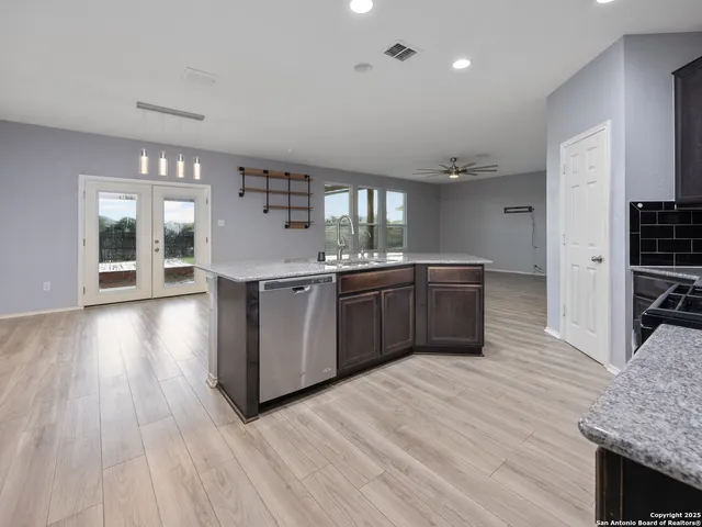 a kitchen with stainless steel appliances granite countertop a sink counter space and wooden floor