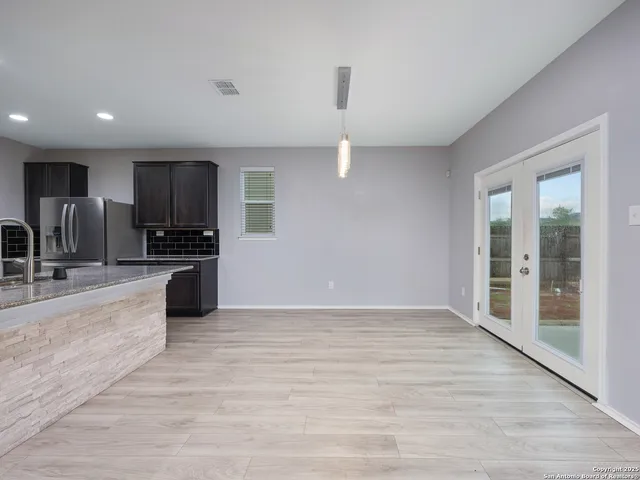 an empty room with kitchen view and wooden floor