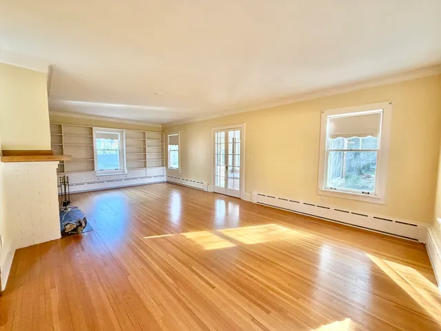 an empty room with wooden floor fireplace and windows